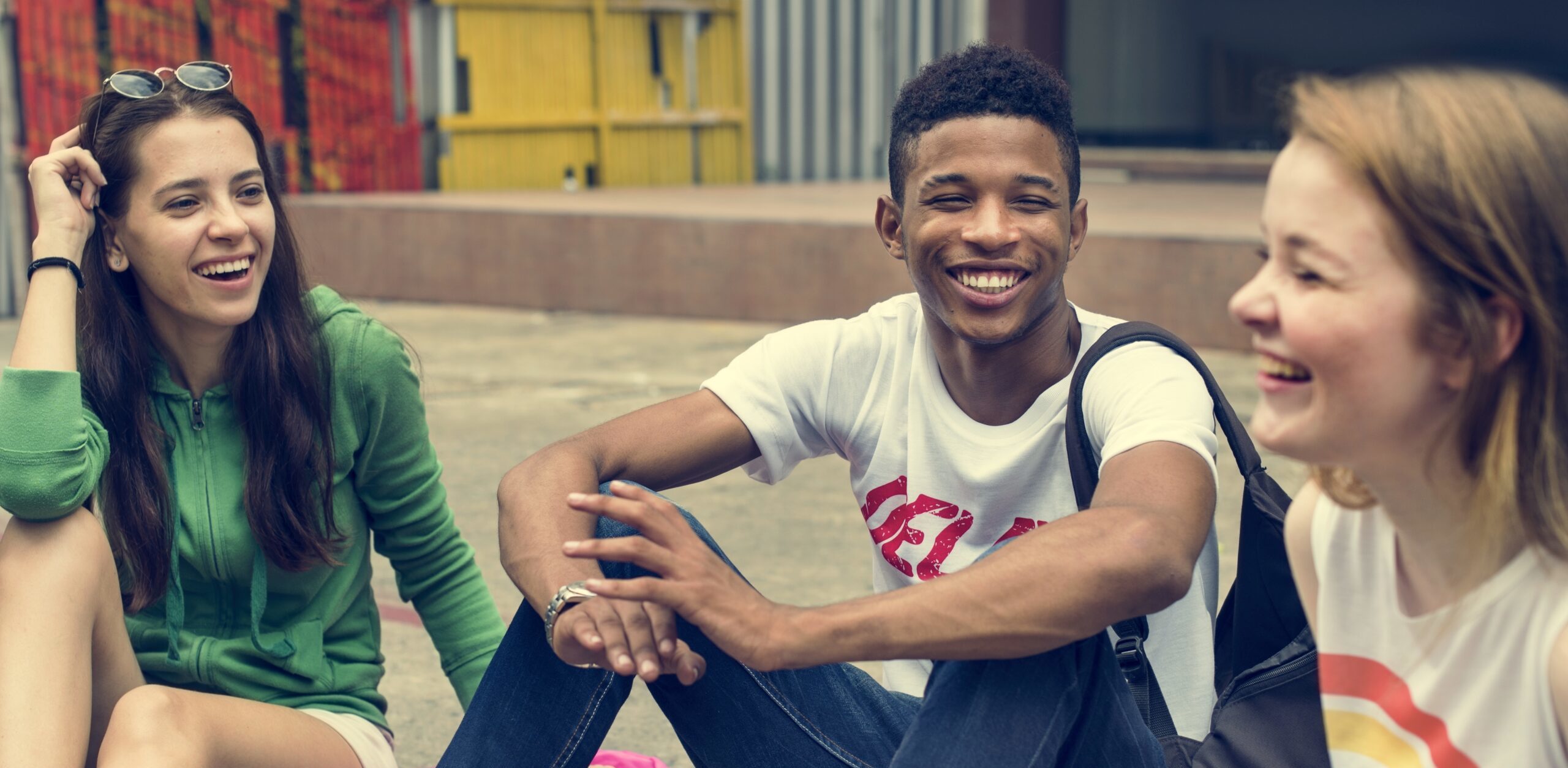 Group of happy teenagers laughing sitting in group on floor