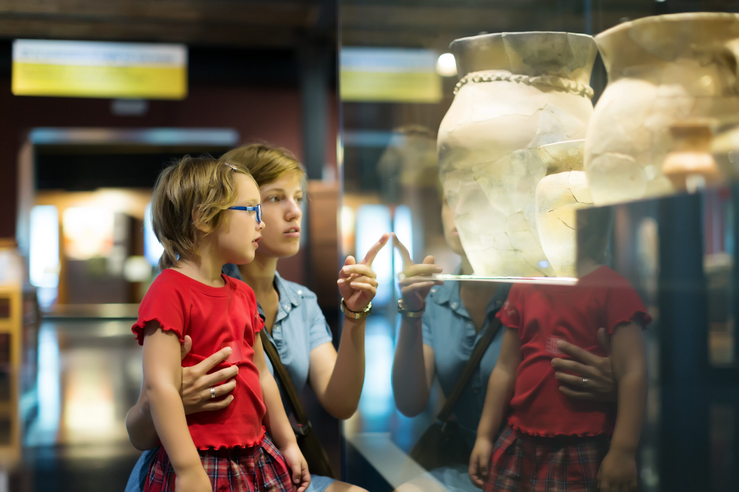 Child and adult looking in glass museum cabinet together